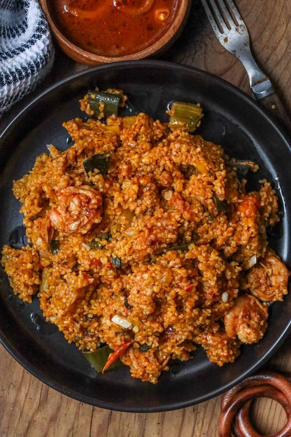 Mayi moulin with shrimp in black bowl with sauce on the wooden spoon