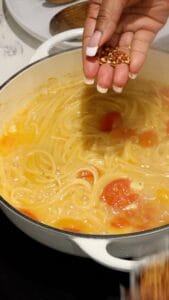 adding red pepper flakes to boiling pasta