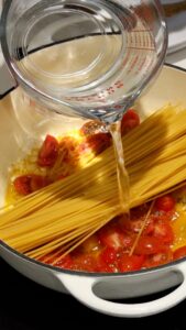 Adding water to pasta and tomato mixture