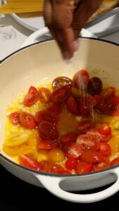 seasoning tomatoes in skillet with onions and garlic