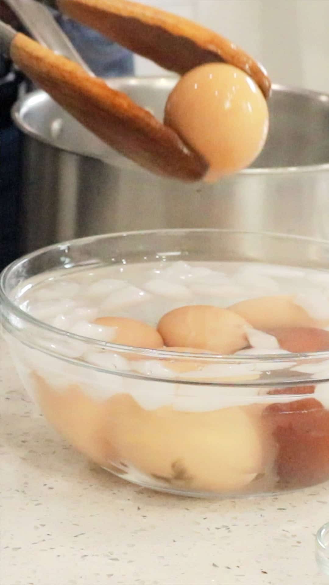 adding cooked boiled eggs to ice bath
