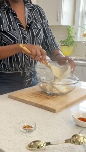 hand pouring dressing onto crab lumps and egg yolks