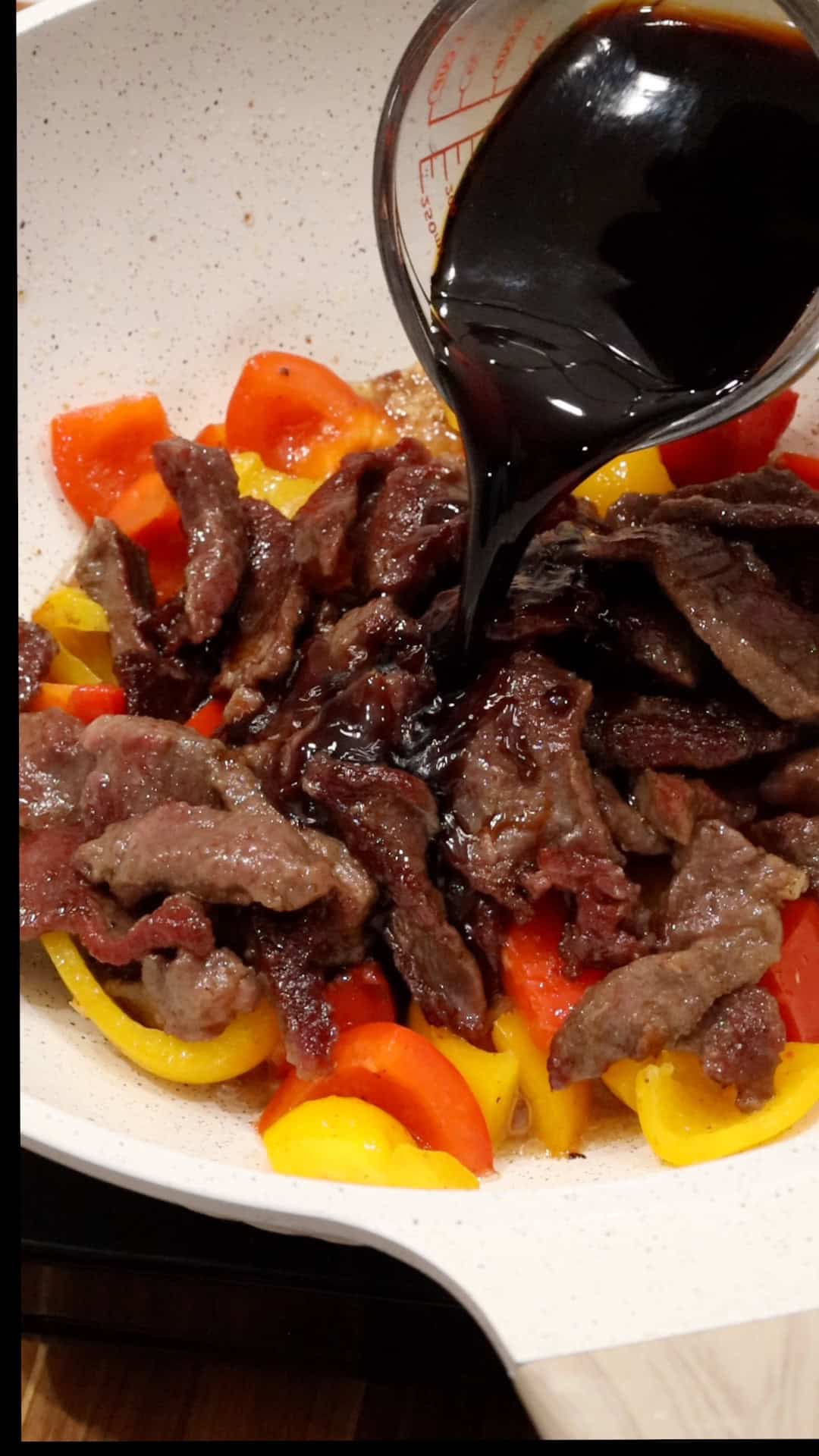 Adding soy sauce to steak and peppers