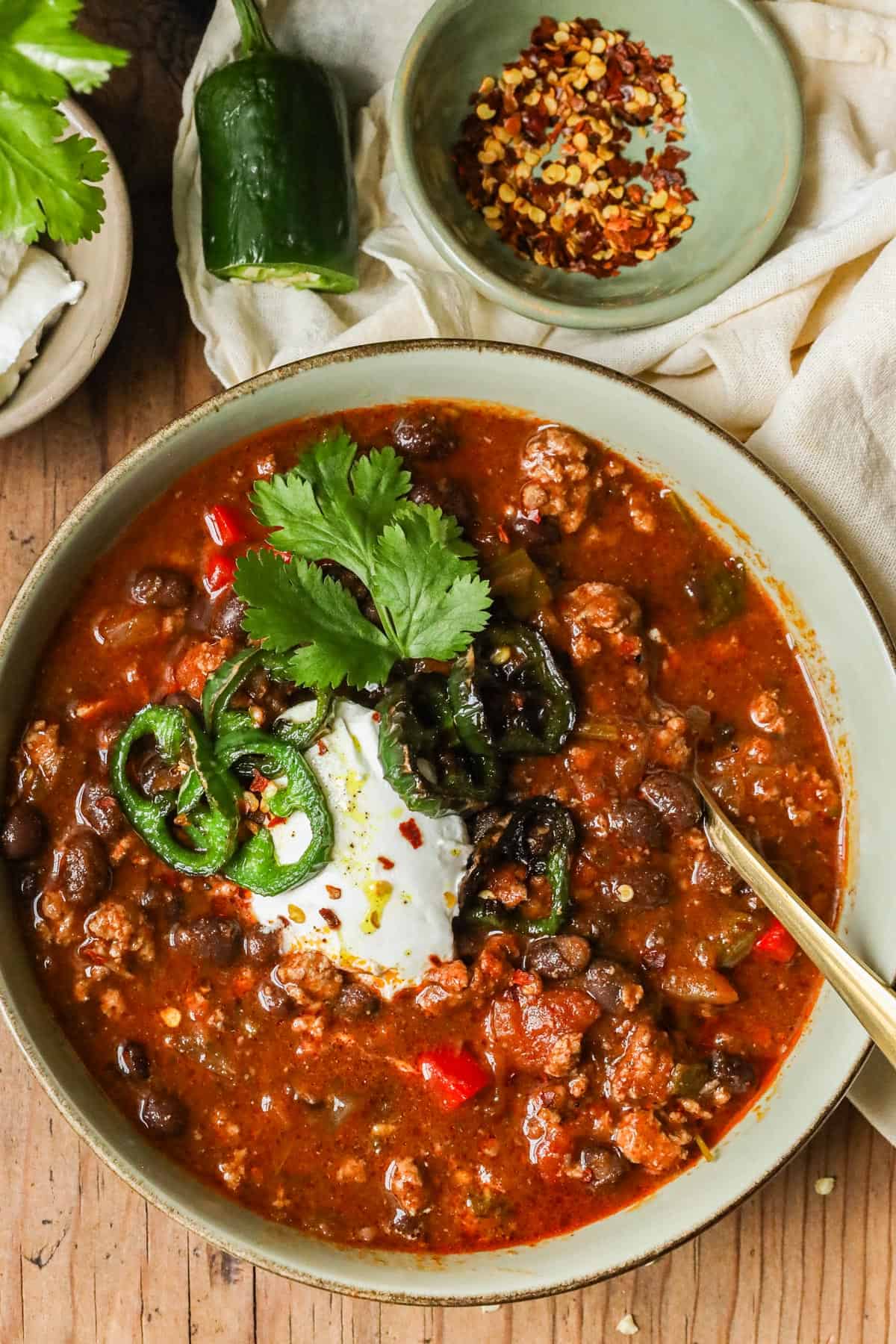 Turkey Bean Chili topped with sour cream, cilantro, and jalapeno peppers, and red pepper flakes