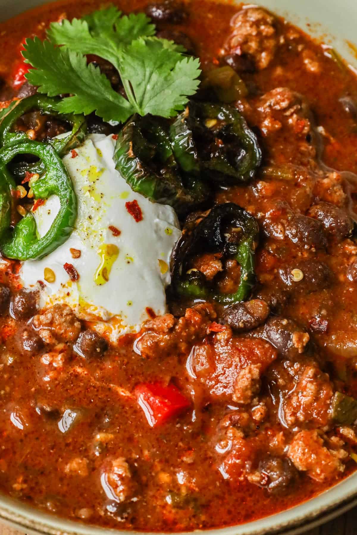 Turkey Bean Chili topped with sour cream, cilantro, and jalapeno peppers