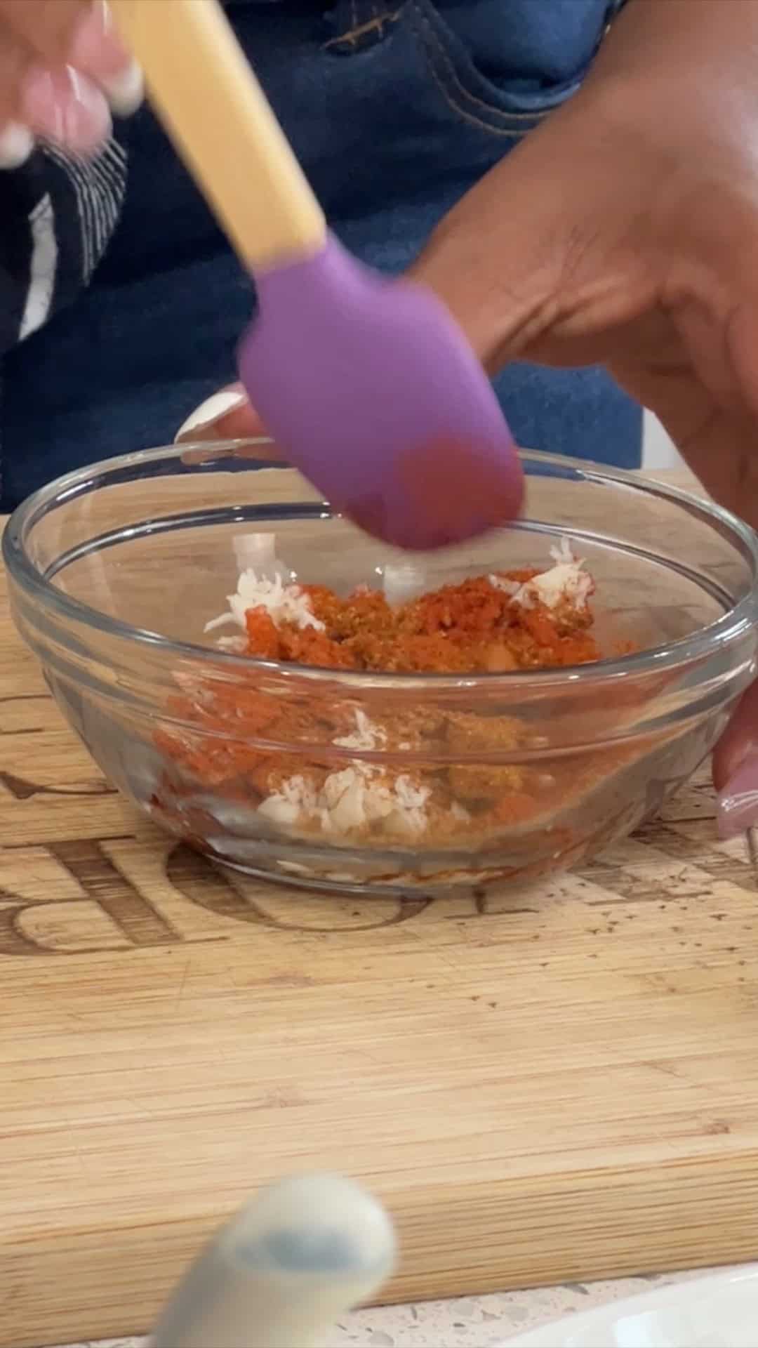 mixing crab meat, paprika, and old bay seasoning in a glass bowl