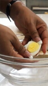 hands scooping out yolk from egg whites