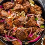 Haitian griot in black bowl topped with red onions