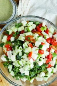 assembling pasta salad in clear bowl