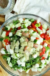 assembling pasta salad in clear bowl