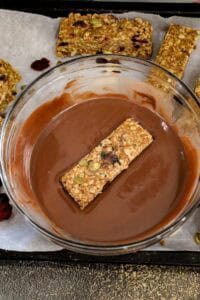 dipping granola bars into chocolate mixture