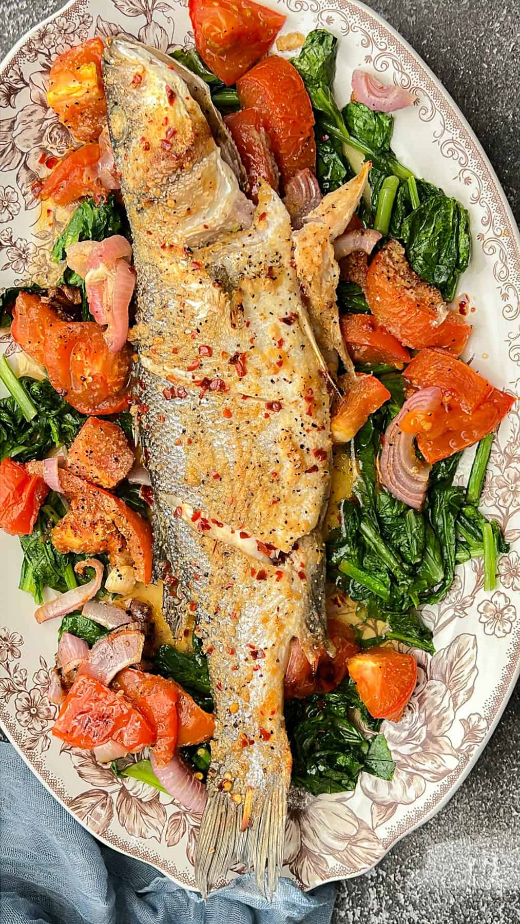 branzino fish on a bed of turnip greens with tomatoes
