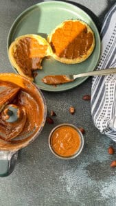 almond butter in a small jar and two waffles topped with the homemade almond butter