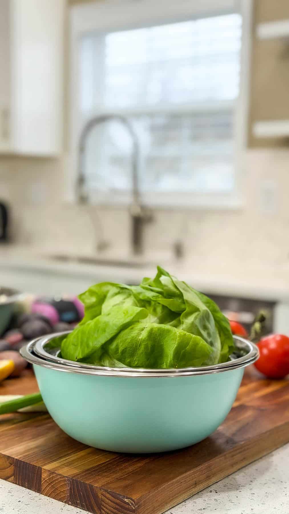 lettuce in a bowl with vegetables in the background