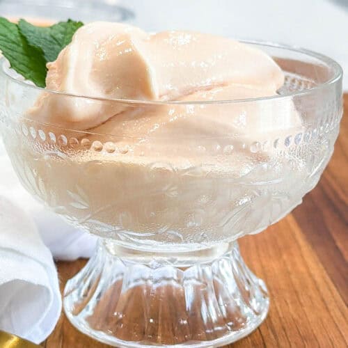 Papaya Ice Cream in glass bowl with mint with spoon on the side