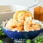 air fryer garlic butter shrimp with parsley and seasoning in the background
