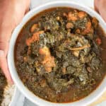 hands holding Collard Greens Chicken Stew with chicken winglets and tender collard greens in seasoned broth in a bowl