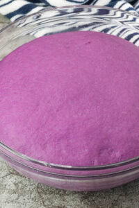 Ube donut dough in clear bowl