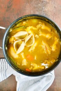 Chicken Soup Joumou (Haitian Chicken Pumpkin Soup) in stockpot with vegetables and noodles