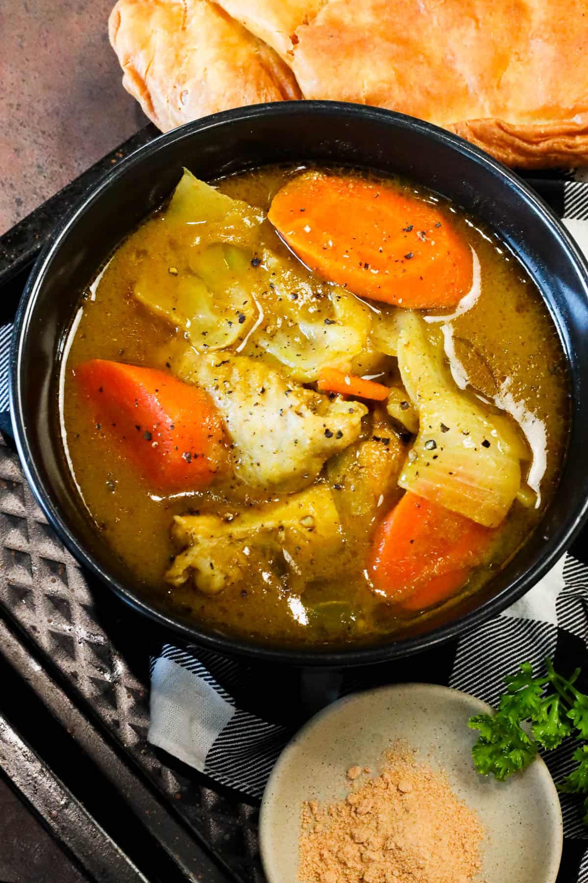 Chicken Soup Joumou with chicken, pumpkin, vegetables, and jumbo pasta shells in black bowl