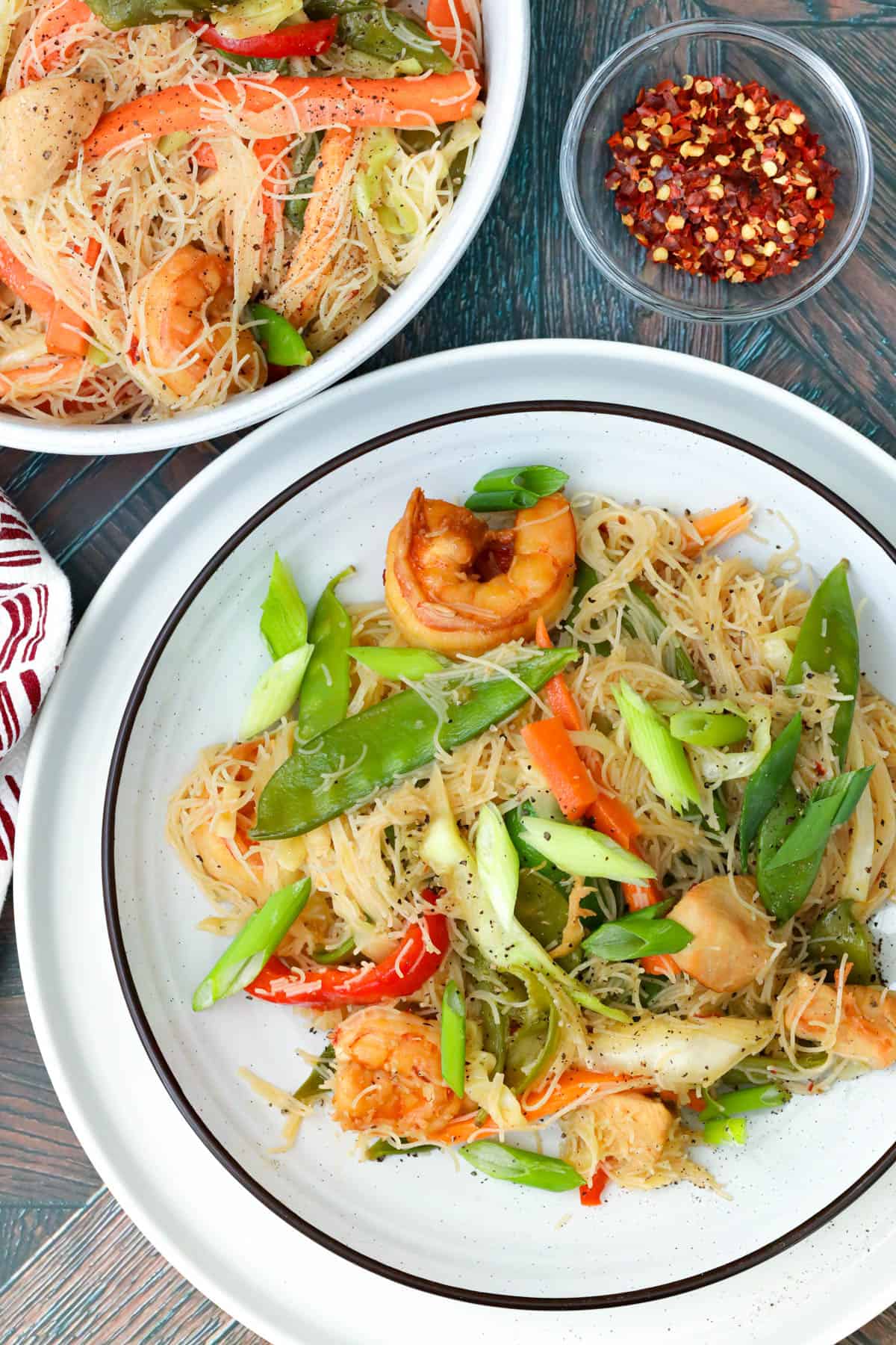 Filipino Pancit Bihon topped with veggies, chicken and shrimp