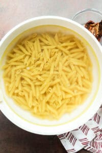 Penne pasta cooking in a large pot of boiling water for Marry Me Chicken Pasta